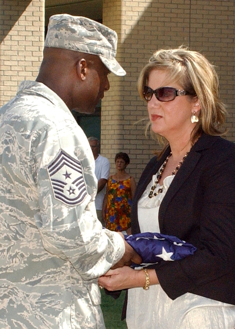 Chief Master Sgt. Juan Lewis, 502nd Air Base Wing command chief, presents the flag to Marie Campbell during a retreat ceremony June 25. Ms. Campbell's husband, Sgt. Millard Dee Campbell, was among 19 Airmen killed during a terrorist attack at Khobar Towers in Dhahran, Saudi Arabia. (U.S. Air Force photo/Sid Luna)