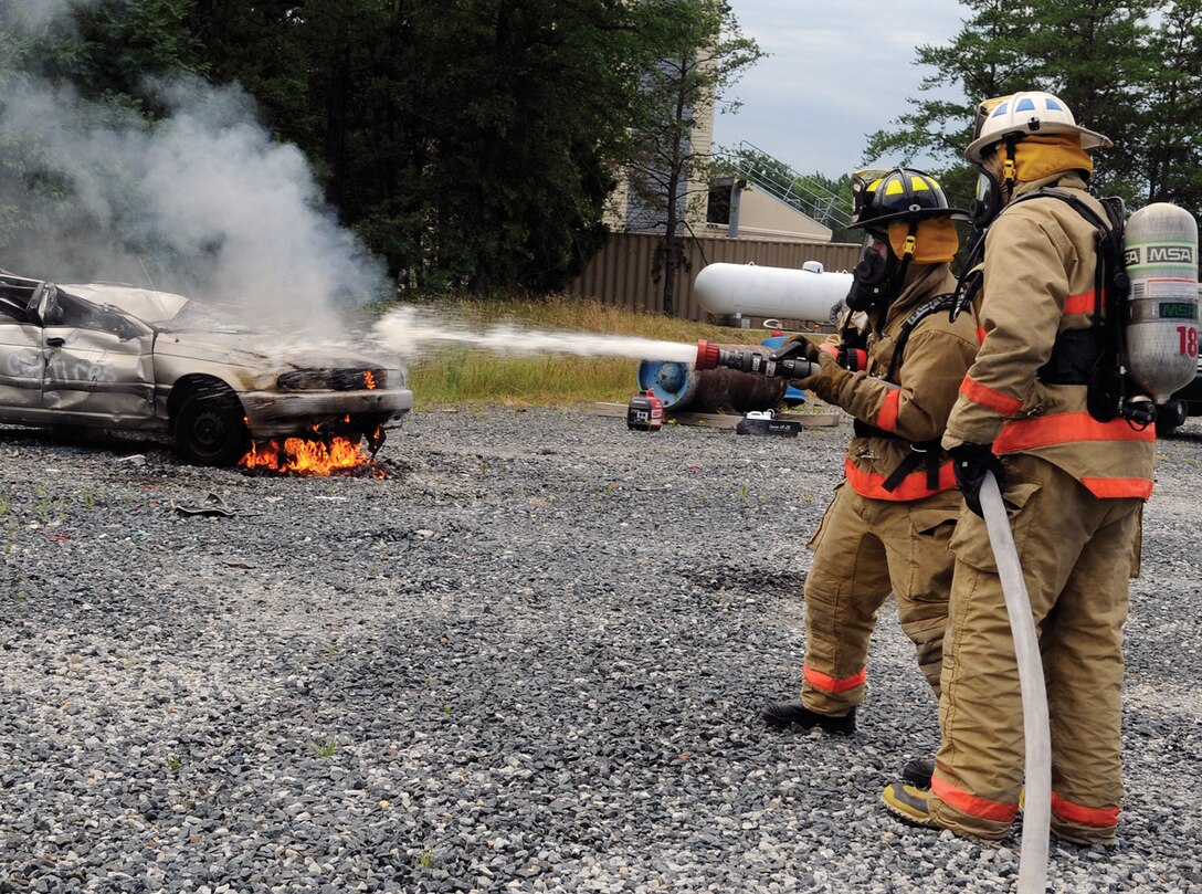 Members of the 316th Civil Engineer Squadron fire department use a fire hose to extinguish a fire for an auto extraction training exercise on Joint Base Andrews June 29. The fire department runs exercises two to three times per month. (U.S. Air Force photo/ Senior Airman Melissa Brownstein)