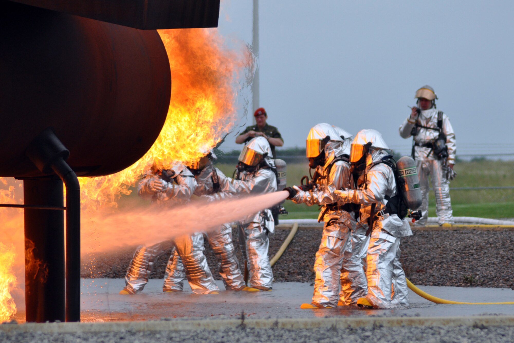 YOUNGSTOWN AIR RESERVE STATION, Ohio -- Members of the U.S. Air Force Reserve's 910th Civil Engineer Fire Department conduct a simulated aircraft fire demonstration as German reserve officer Lt. Col. Patrick Hofmann looks on at the wing?s fire pit June 17. Colonel Hofmann, a public affairs officer assigned to the German Joint Supprt Service, visited the Youngstown Air Reserve Station along with Lt. Col Stefan Bernreider, a judge advocate officer assigned to the German Air Force Reserve , June 12-26, as part of the Department of Defense Reserve Officers Exchange Program. The primary purpose of the exchange program is to provide National Guard and Reserve officers training associated with mobilization duties while enhancing their ability to work and communicate with the military individuals of the host nation. Reserve officers who participate in the exchange program receive valuable training, which they are able to share with their home units.  They gain an appreciation of allied Reserve forces, which facilitates an effective working relationship with those forces upon mobilization. The Office of the Assistant Secretary of Defense (Reserve Affairs) oversees this program since its inception in 1985. U.S. Air Force photo by Master Sgt. Bob Barko Jr. 