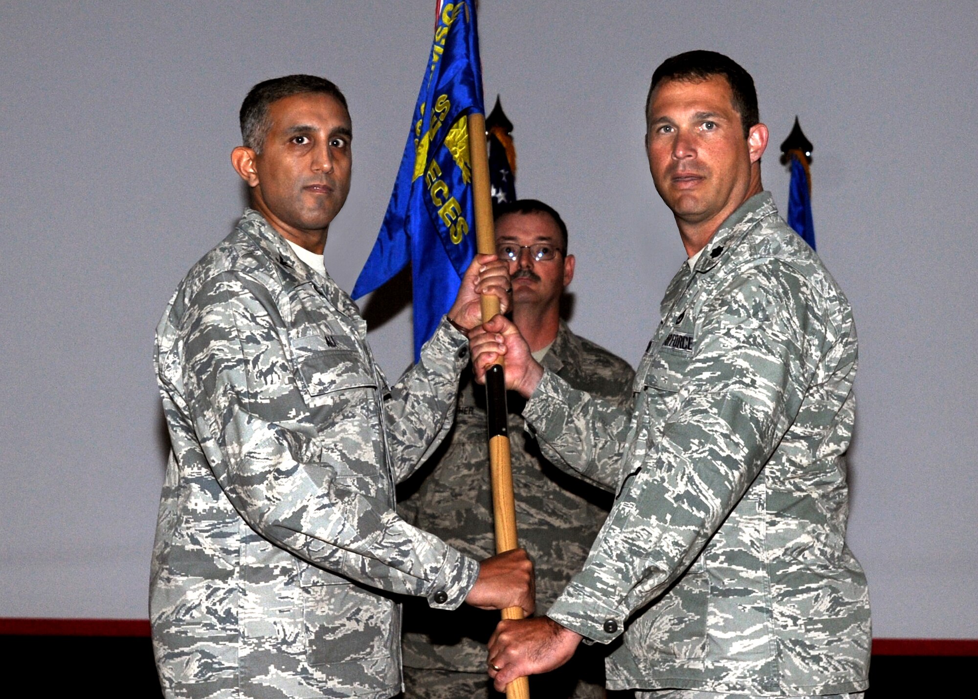 SOUTHWEST ASIA - U.S. Air Force Col. Rizwan Ali (left), 386th Expeditionary Mission Support Group commander, passes the 386th Expeditionary Civil Engineer Squadron guidon to Lt. Col. Ronald Pieri, the new 386th ECES commander, during a change-of-command ceremony here July 1, 2010, at the base theater. Colonel Pieri assumed command after Lt. Col. Matthew Bobb relinquished command. (U.S. Air Force photo by Senior Airman Laura Turner/Released)