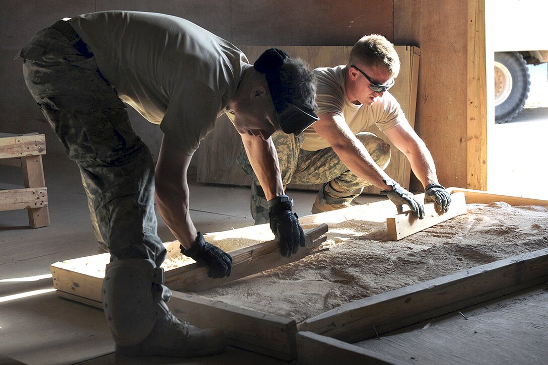 U.S. Army Spc. Brandon Crane, right, and Spc. Jake Clark work together to build a sand table on Camp Kassum, Al Asad Air Base, Iraq, June 22, 2010. Crane and Clark are assigned to the 82nd Airborne Division's Company B, 1st Battalion, 504th Parachute Infantry Regiment, 1st Advise and Assist Brigade. The soldiers were at the Iraqi Army base to train the Iraqi soldiers on air assault operations using a sand table to familiarize themselves with the terrain.