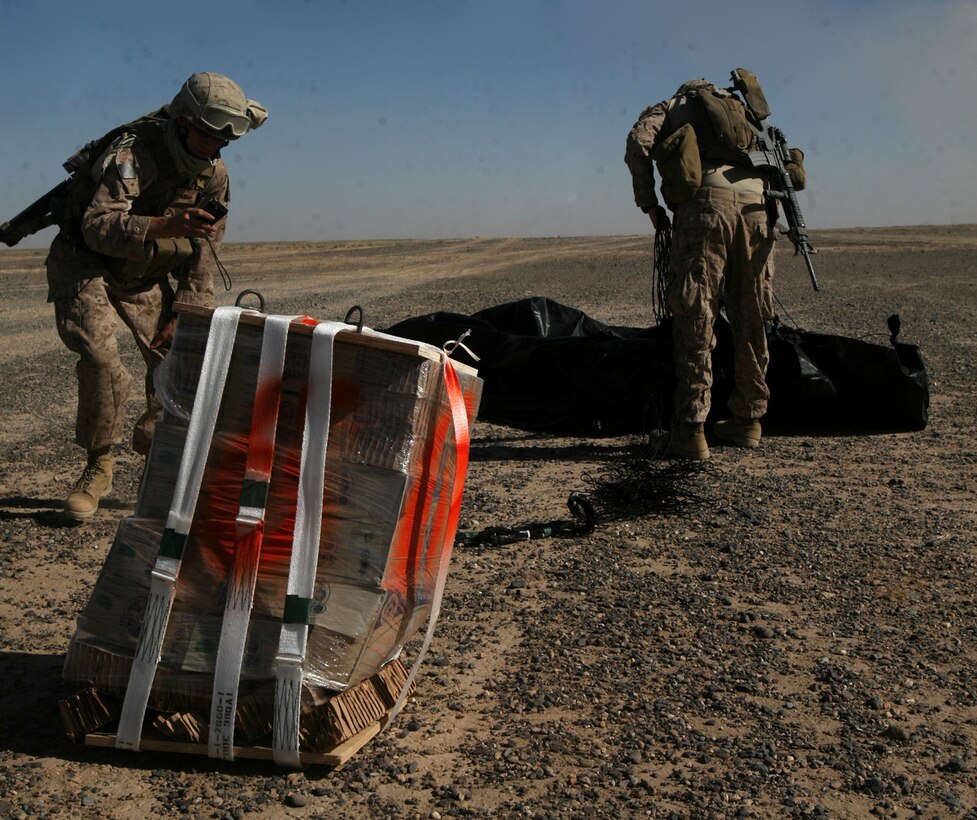 Lance Cpl. Jordan Shemanski (left), air delivery specialist with 1st Marine Logistics Group (Forward), documents the condition of a bundle of bottled water while Lance Cpl. Cory J. Bandouveres, air delivery specialist with 1st MLG (FWD), recovers a Low Cost Low Altitude parachute canopy during a training operation conducted near Forward Operating Base Dwyer July 1. The Marines made several small drops of packaged water bottles at altitudes ranging from 150 to 900 ft. in order to test the capabilities of these new and cost effective canopies. Unlike previous parachutes used, these are considered one-time use and will be used to supply ground troops with critical items such as food and water.