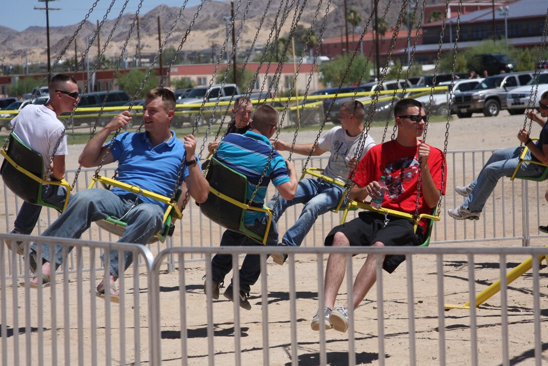 Marines and family members ride on the swings during the 1st battalion, 7th Marine Regiment, Family Day event at the soccer field by the physical fitness test course July 2.