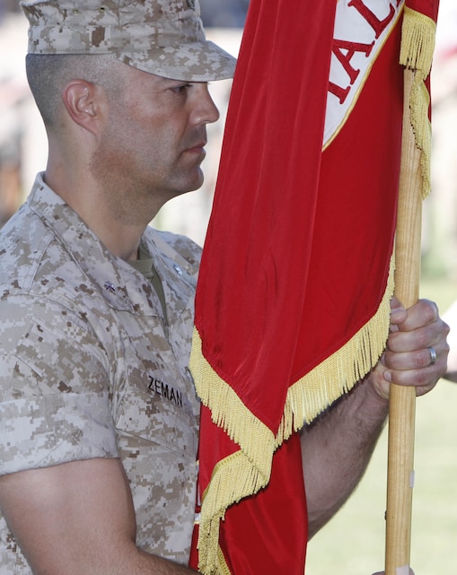 Lieutenant Col. Phillip Zeman, the new commanding officer of the Combat Center’s Headquarters Battalion, holds the unit’s ensign as Sgt. Maj. James D. Walsh [right] the unit’s sergeant major salutes him, during a change of command ceremony at the installation’s Lance Cpl. Torrey L. Gray Field July 2. Zeman replaced Lt. Col. Brandon D. McGowan as the commanding officer.