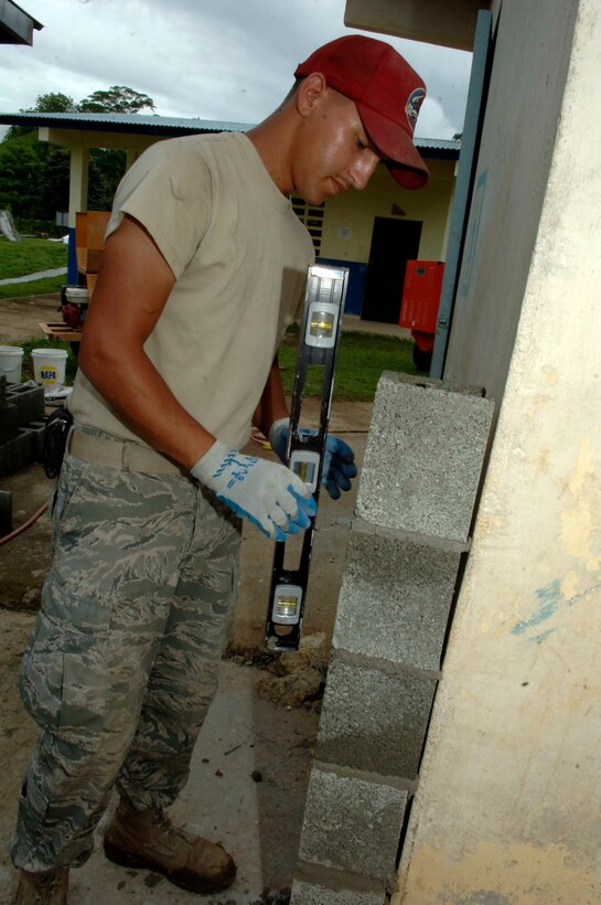 Airman 1st Class Scott Gomez, 820th Expeditionary RED HORSE Squadron, levels concrete block for a new bathroom at Sanson Elementary School July 2. (U.S. Air Force photo/Tech. Sgt. Eric Petosky)