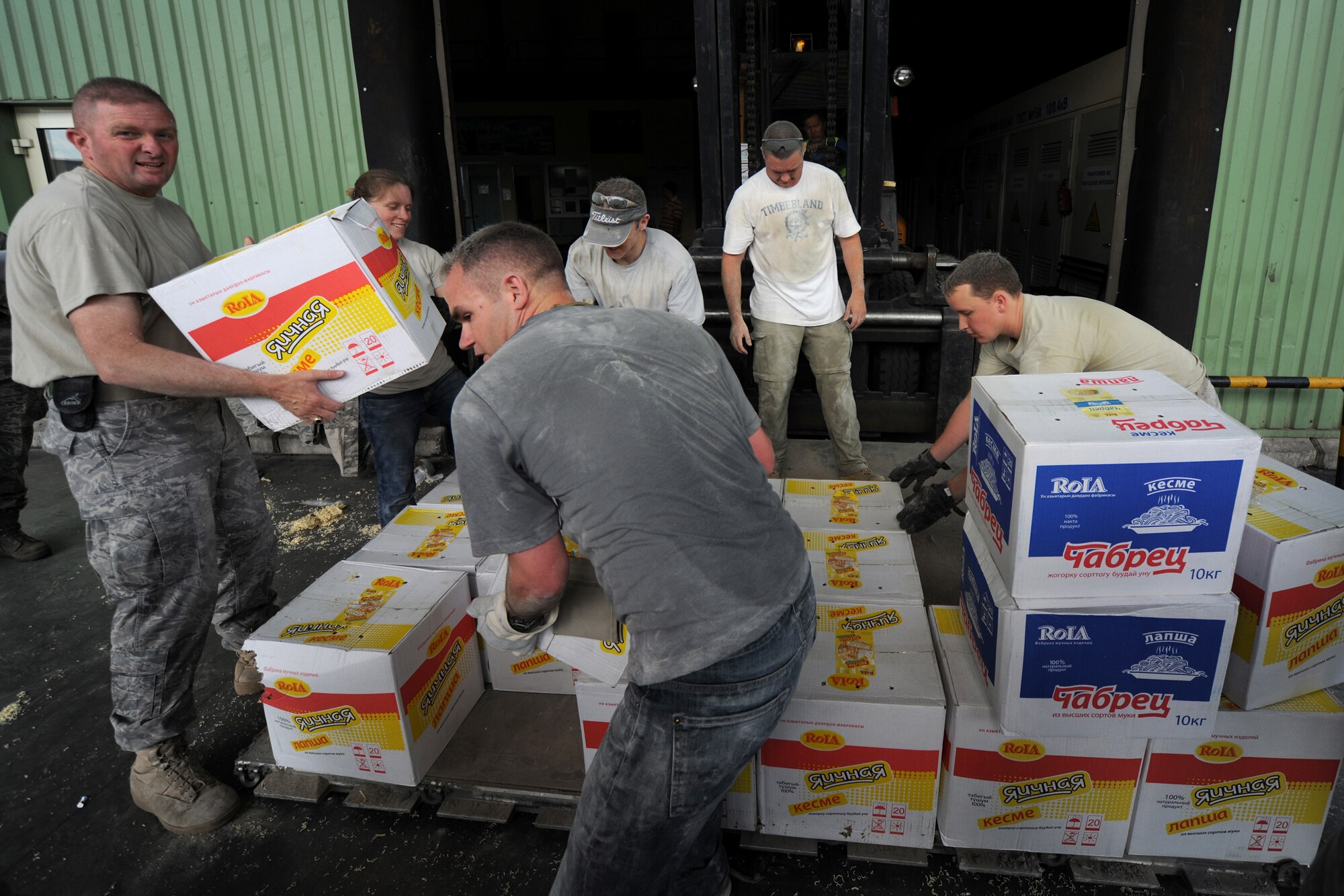 MANAS INTERNATIONAL AIRPORT, Kygryzstan - Command Chief Master Sgt. Chief Master Sergeant James Dowell, left, and Capt. Carl McBurnett, Jr., right, were among 20 Airmen who volunteered to help Kyrgyz relief workers, at the Manas International Airport warehouse, load eight pallets into an 18-wheeler headed for Osh July 3. (U.S. Air Force photo/Staff Sgt. Michael Schocker)