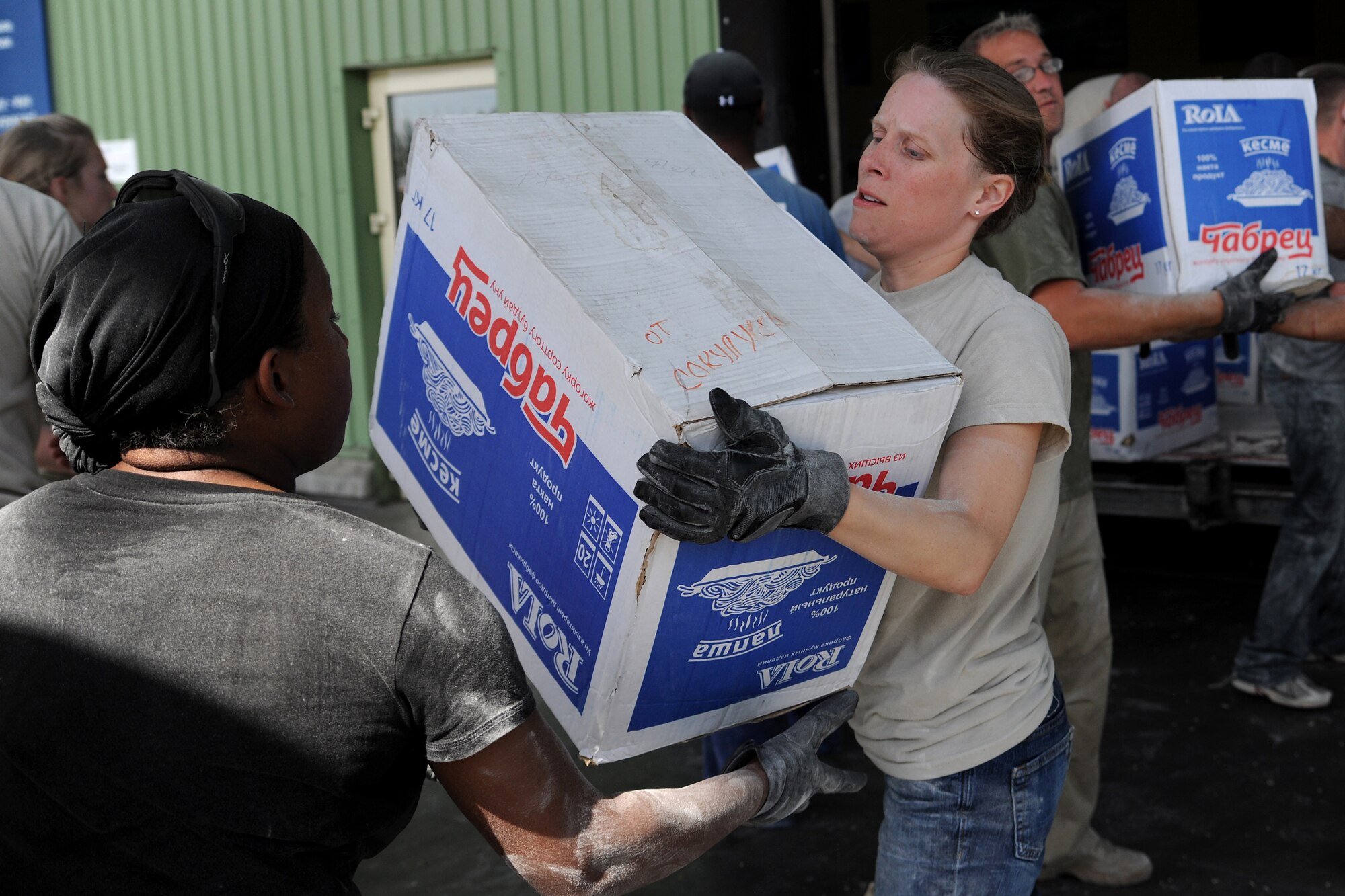 MANAS INTERNATIONAL AIRPORT, Kygryzstan - Tech. Sgt. Jessica Jenkins passes a box of noodles to Staff Sgt. Brandi Baker in a line of about 20 Airmen who volunteered to help Kyrgyz relief workers, at the Manas International Airport warehouse, load eight pallets into an 18-wheeler headed for Osh July 3. (U.S. Air Force photo/Staff Sgt. Michael Schocker)
