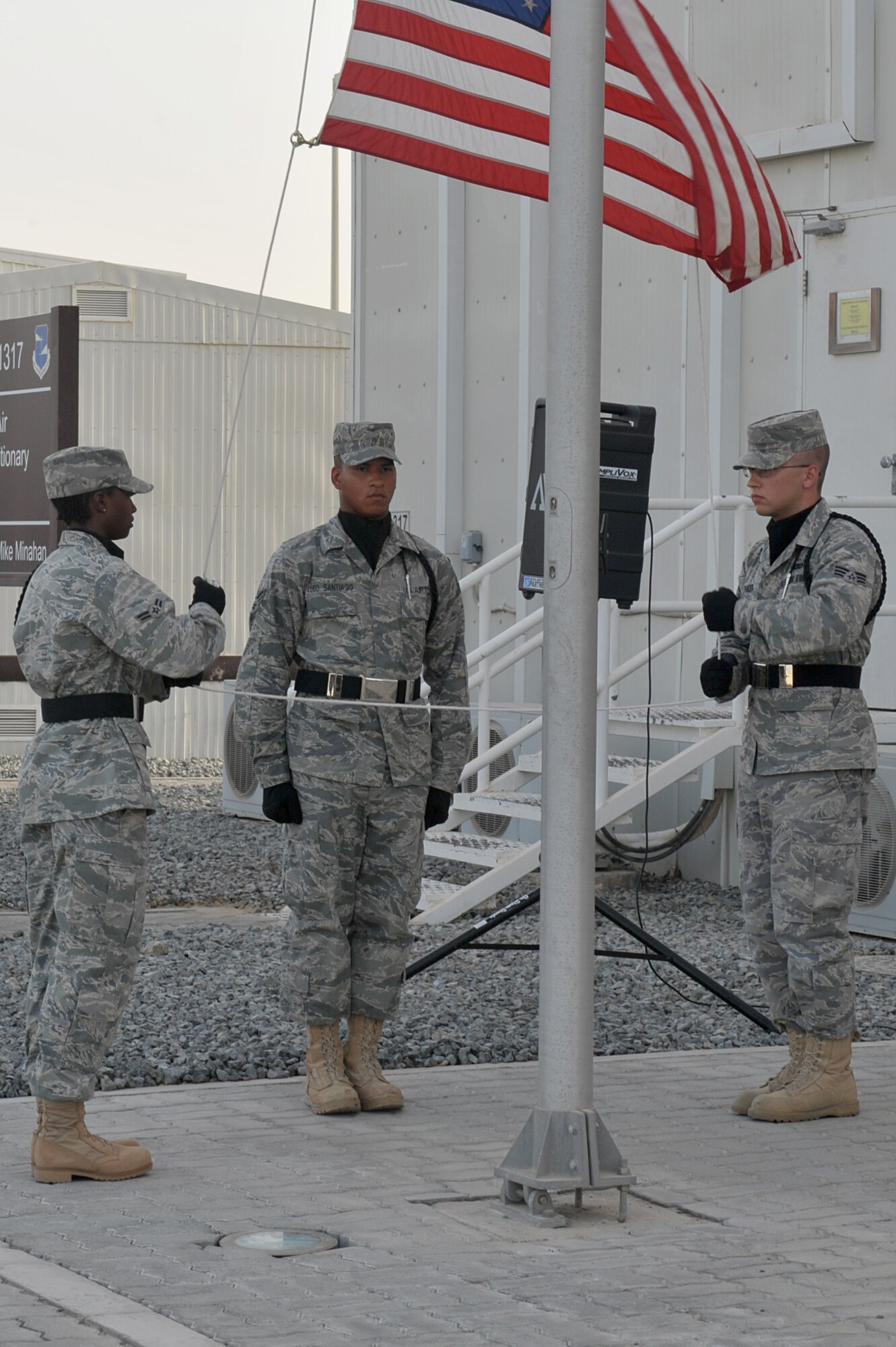 Airman 1st Class Allyson Pendleton, Senior Airman Axel Lugo Santiago and Senior Airman Caleb Wanzer lower the flag during a retreat ceremony July 2 at an undisclosed location in Southwest Asia.  Retreats are held weekly at this non-disclosed base. (U.S. Air Force photo/ Tech. Sgt. April Wickes)