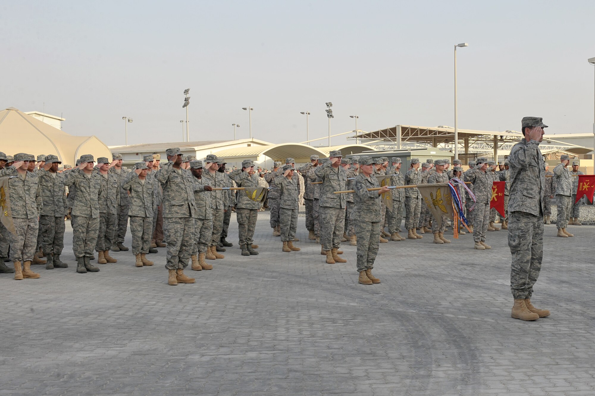 Airmen from the 380th Air Expeditionary Wing and Army soldiers salute the American flag during a retreat ceremony July 2 at an undisclosed location in Southwest Asia.  This was the last retreat here for Command Chief Master Sgt. Suzan Sangster, she received a Bronze Star medal for her tireless contributions to the 380th AEW before the retreat ceremony. (U.S. Air Force photo/ Tech. Sgt. April Wickes)