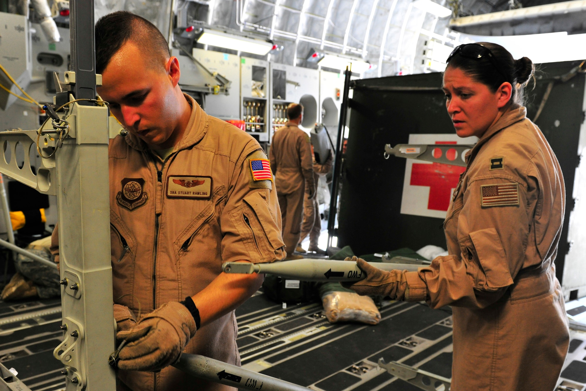 Senior Airman Stuart Rawling and Captain Catherine Paterson assemble litter stanchels for patients on a C-17 Globemaster III at Bagram Airfield, Afghanistan, July 2, 2010. More than 60 U.S. service members were evacuated to a regional hospital for care in Germany. (U.S. Air Force photo/Staff Sgt. Christopher Boitz)