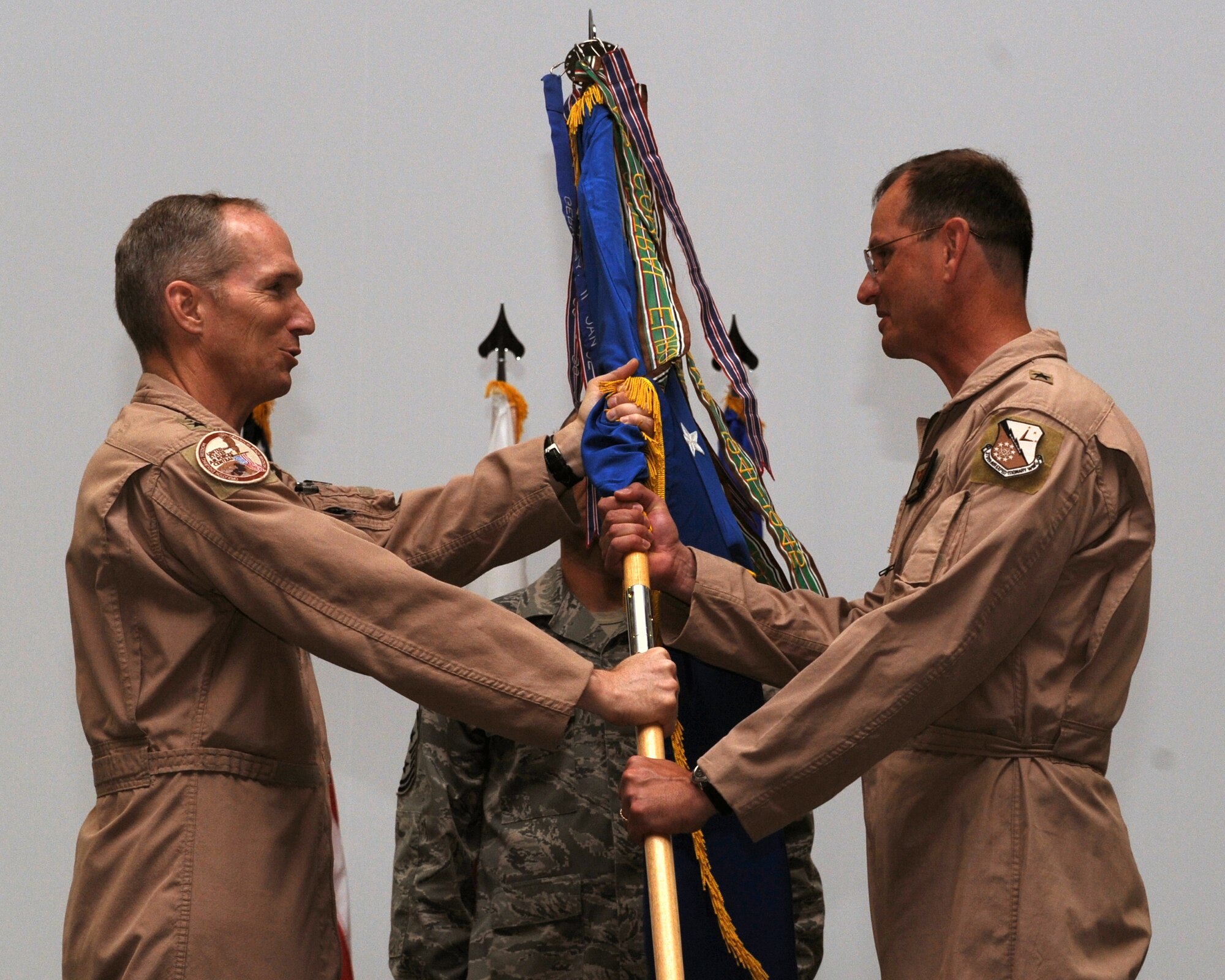 Lt. Gen. Gilmary Hostage III, U.S. Air Forces Central Command commander, passes the 379th Air Expeditionary Wing guidon to Brig. Gen. Randy Kee in a change of command ceremony July 1 in Southwest Asia. General Kee assumed command of the 379th AEW from Brig. Gen. Stephen Wilson. (U.S. Air Force photo/Senior Airman Katie Gieratz)