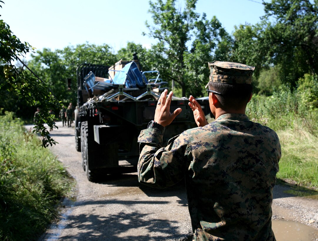 Cpl. Delshan Martinez, a vehicle operator with 1st Tank Battalion, ground guides a 7-ton truck carrying donated toys and furniture to an orphanage in Medven, Bulgaria, July 5.