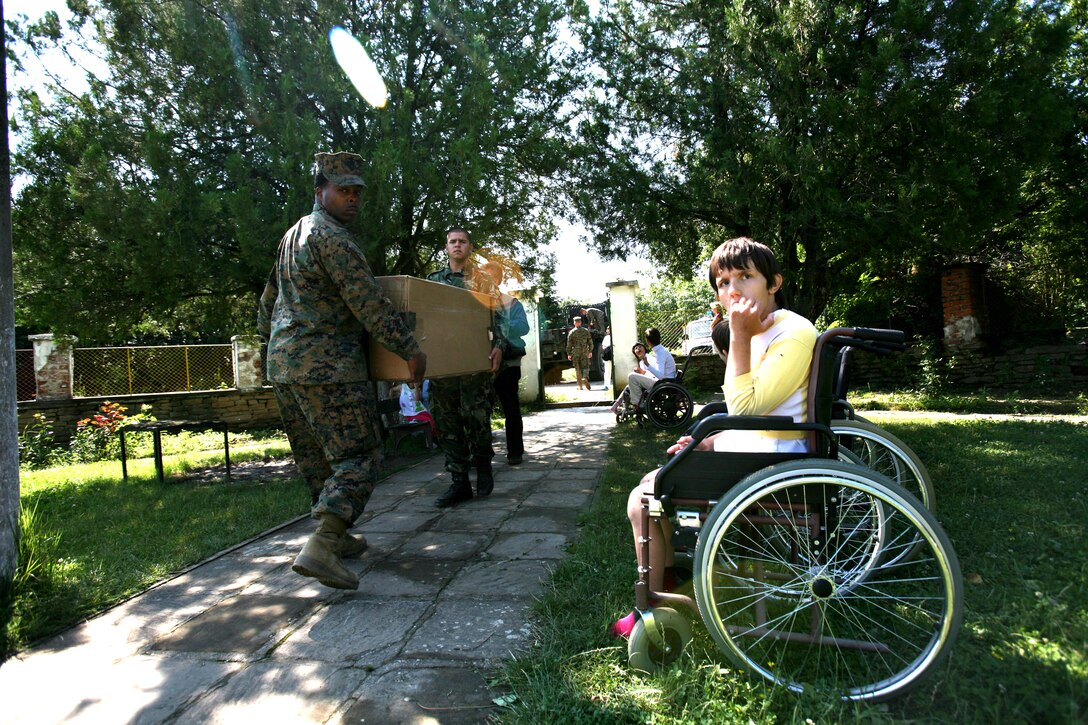 Cpl. Mark C. Davis II, left, and Bulgarian army Pvt. Stoycho Manev carry a box of donated toys to the St. Marina orphanage in Medven, Bulgaria, July 5. Davis is the data systems chief for Black Sea Rotational Force Marines at Novo Selo Training Area, and Manev is a soldier with the 38th Infantry Battalion, 2nd Light Infantry Brigade.