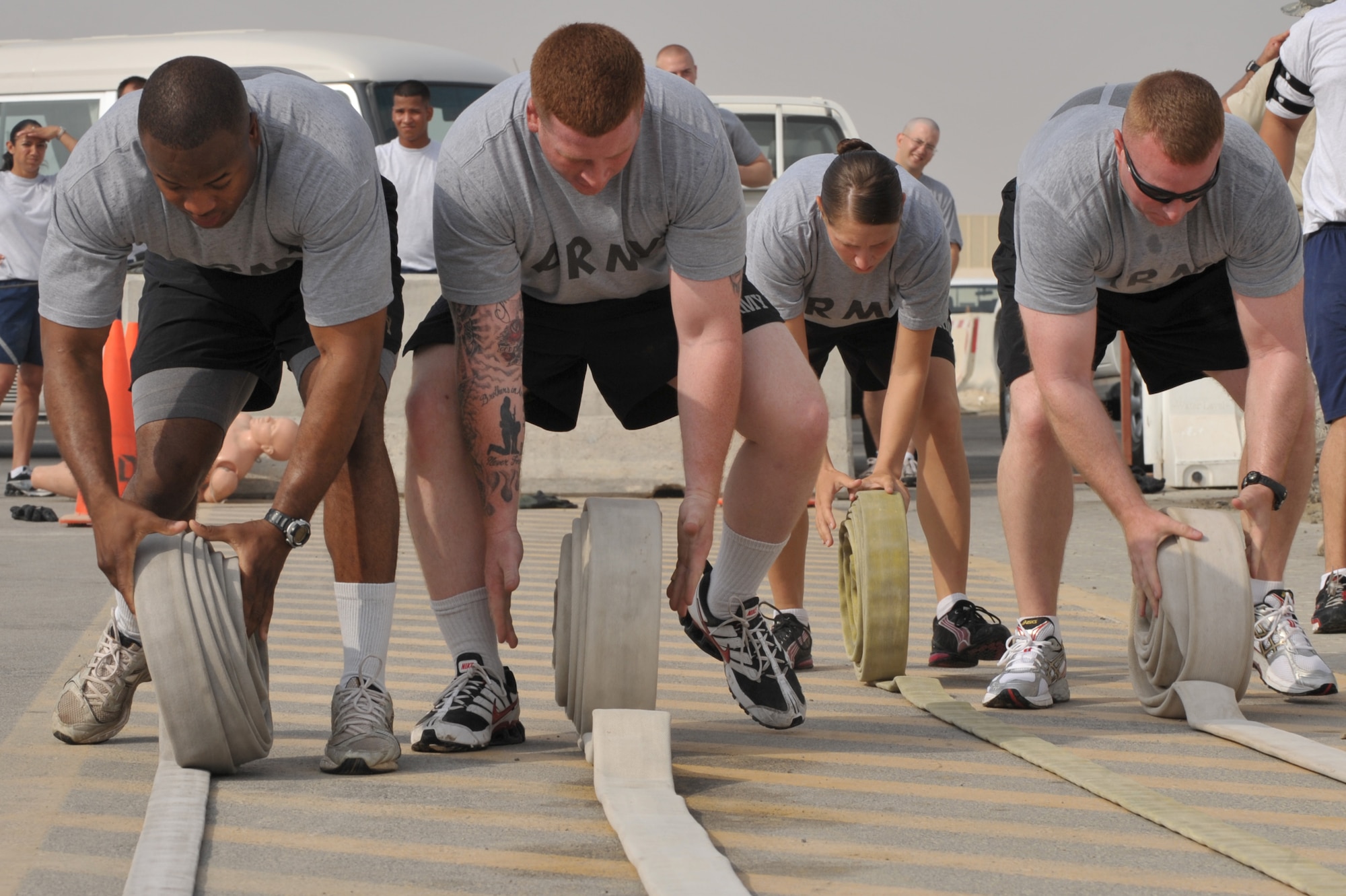 Soldiers roll up fire hoses during the fire muster challenge July 4 at an undisclosed location in Southwest Asia. Air Force cadets, Airmen, and Soldiers participated in the event with Cadet team 2 winning. (U.S. Air Force photo/Tech. Sgt April Wickes) 