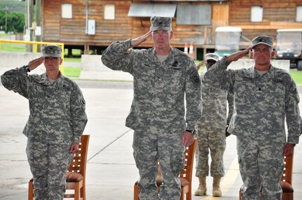 SOTO CANO AIR BASE, Honduras --  Col. Marie Dominguez, left, and Lt. Col. Michael Hoilien, right, stand on either side of Col. Gregory Reilly, the Joint Task Force-Bravo commander, and hold a salute during the playing of the Honduran and U.S. national anthems at the Medical Element change of command ceremony here June 17. Colonel Hoilien took command of MEDEL from Colonel Dominguez. (U.S. Air Force photo/Martin Chahin)