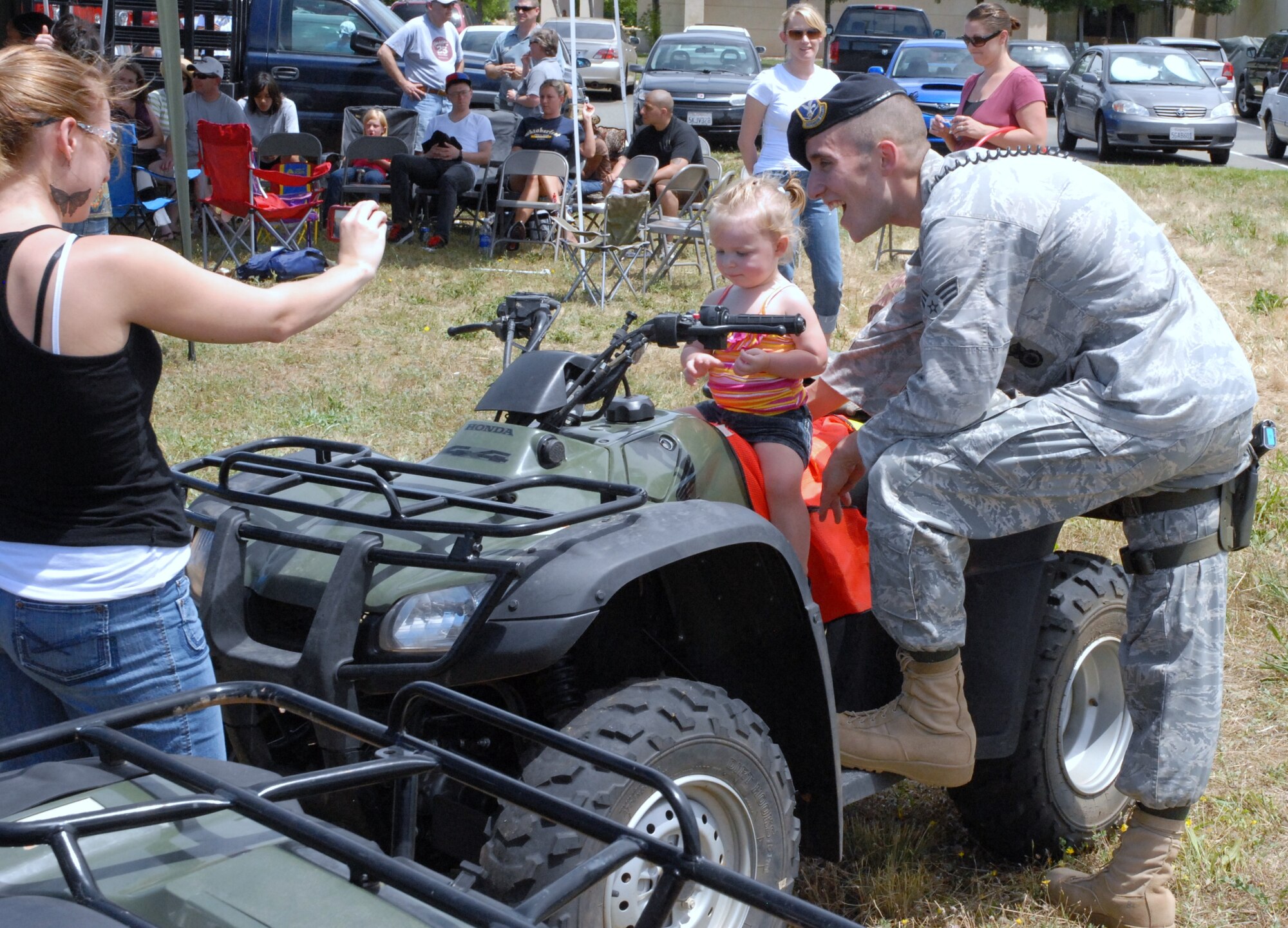 A member of the security forces takes a picture with his daughter on an ATV. (U.S. Air Force Photo/A1C Adam Hamar)