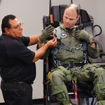 Rey Gutierrez, 12th Operational Support Squadron, goes over  procedures for connecting parachute harnesses to the new T-38C ejection seat while Maj. Bryan France, 435th Flying Training Squadron, connects his harness shoulder straps to the seat June 30. The new seat replaces the carried parachute with a harness and in-seat chute, has zero/zero capability and includes a redesigned parachute.(U.S. Air Force photo/Steve Thurow)