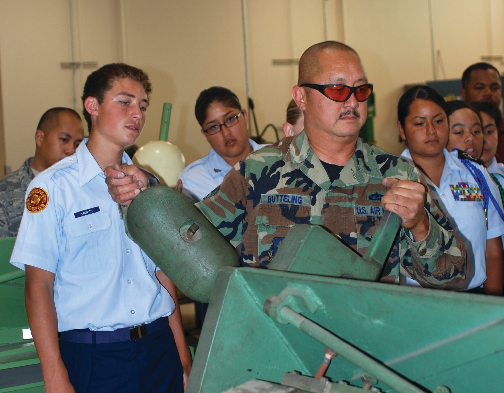 Junior ROTC cadets watch as Tech. Sgt. Arthur Butteling demonstrates the use of a box and pan brake, which is one of the pieces of equipment in the 452nd Maintenance Squadron sheet metal fabrication shop. The brake can bend flat metal into a variety of angles. (U.S. Air Force photo by Megan Just)