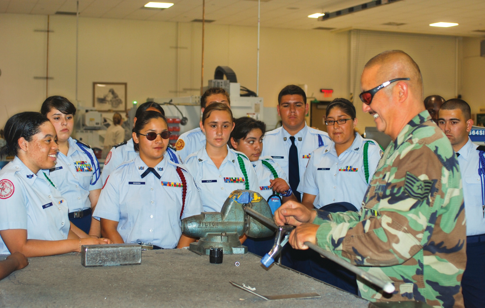 Junior ROTC cadets watch as Tech. Sgt. Arthur Butteling cuts a metal rod with a manual tube cutter. The device can cut tubing in a range of diameters and materials, including steel and aluminum. (U.S. Air Force photo by Megan Just)