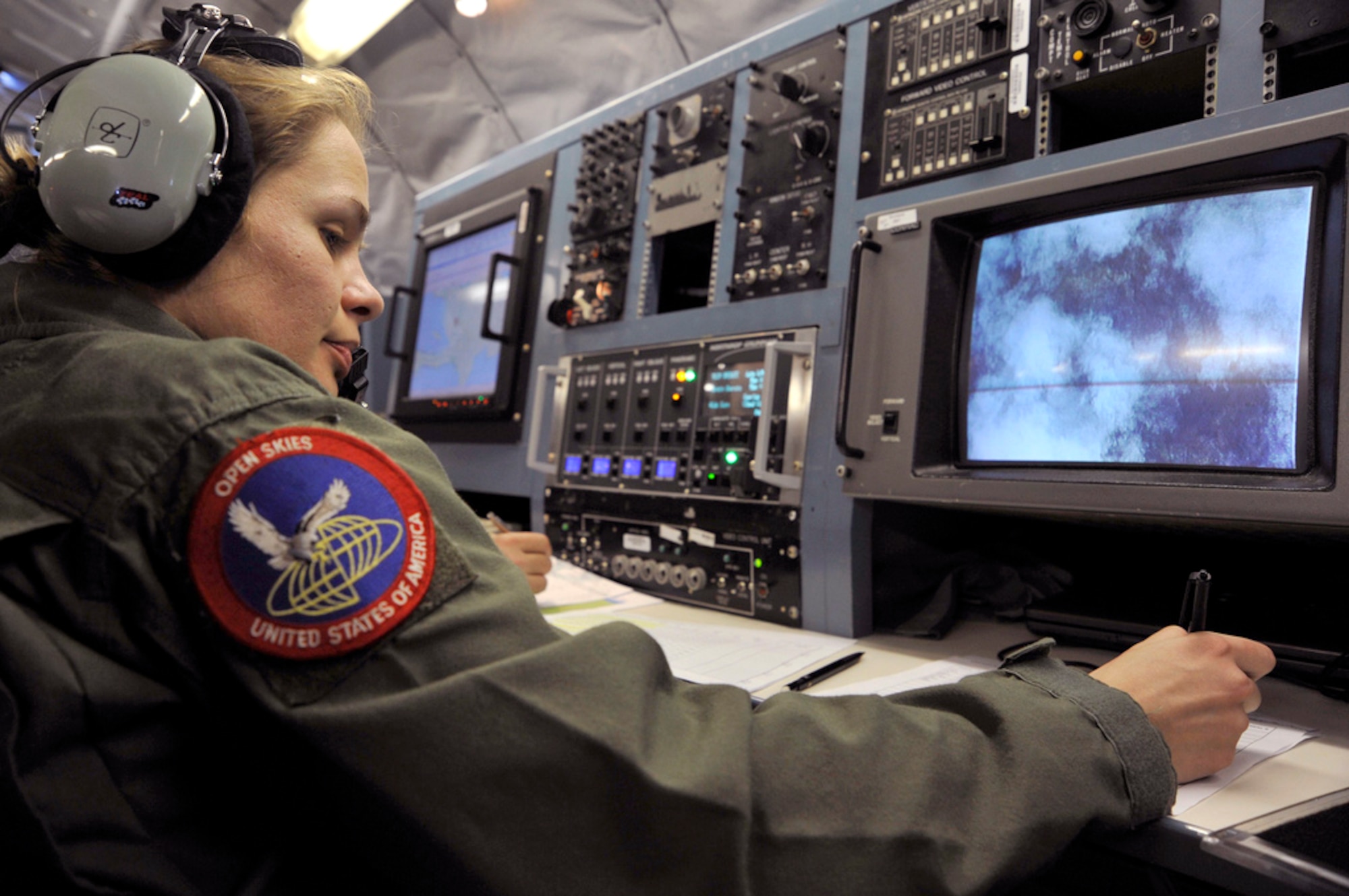 Staff Sgt. Agne Mileviciute writes in a mission log Jan. 16, 2010, as pictures are taken over Haiti by an OC-135B Open Skies observation aircraft. (Department of Defense photo/Airman 1st Class Perry Aston)