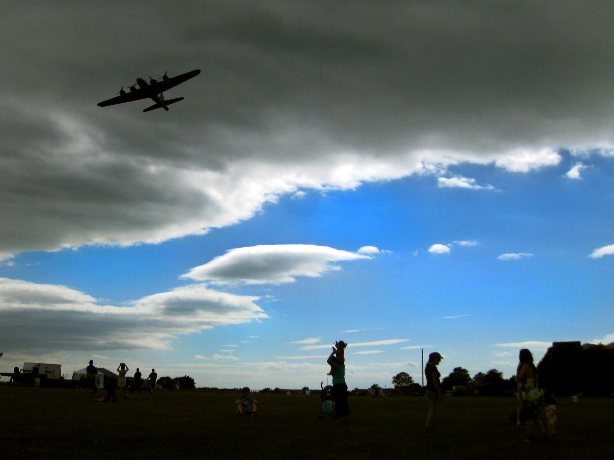 Spectators watch as a B-17 Flying Fortress flies past the Independence Day Celebration at RAF Feltwell July 4. Everyone, including civilians and military, were invited to the annual event which included games, live bands, carnival rides and an HH-60 helicopter display from the 56th Rescue Squadron. The event concluded with a fireworks display celebrating 234 years of American independence. (U.S. Air Force photo/Tech. Sgt. Nathan Gallahan)