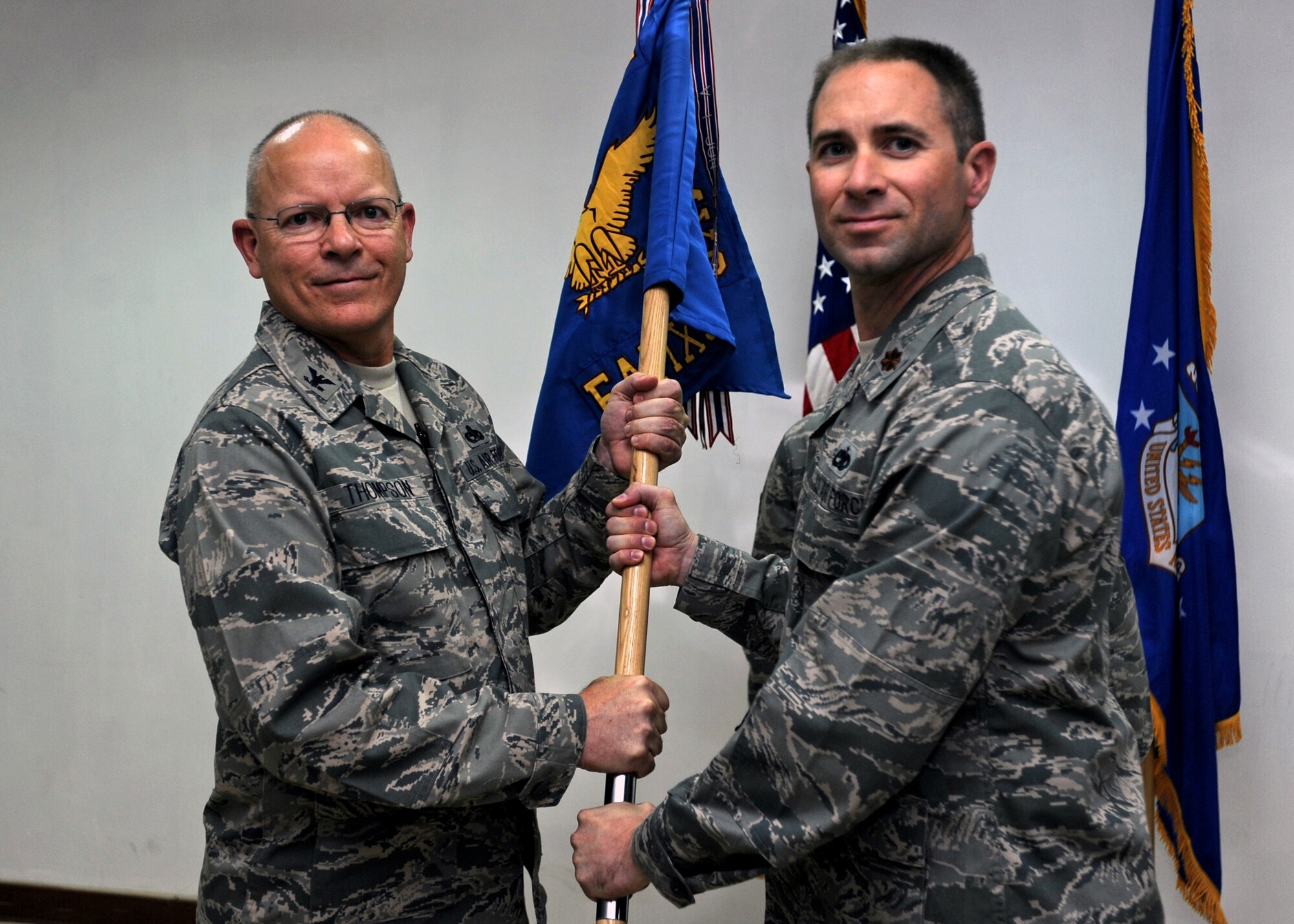 SOUTHWEST ASIA - Col. Ricky Thompson, 386th Expeditionary Maintenance Group commander, passes the 386th Expeditionary Aircraft Maintenance Squadron guidon to Maj. Chad Scholes, the new 386th EAMXS commander, during a change-of-command ceremony at an undisclosed base here July 5, 2010. Major Scholes assumed command after Maj. Christopher MacAulay relinquished command. (U.S. Air Force photo by Senior Airman Laura Turner)