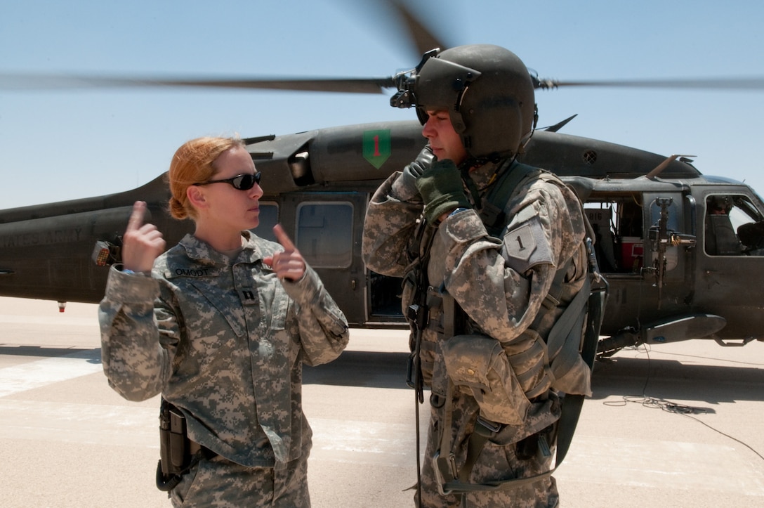 Army Capt. Catherine Omodt speaks with a crew chief of a UH-60 Black Hawk helicopter at Al Asad Air Base, Iraq, June 27, 2010. Omodt, a Black Hawk pilot, is in charge of managing passenger travel for her brigade’s 4,000 paratroopers back to Fort Bragg, N.C., following a yearlong deployment in Iraq’s Anbar province. U.S. Army photo by Sgt. Michael J. MacLeod 