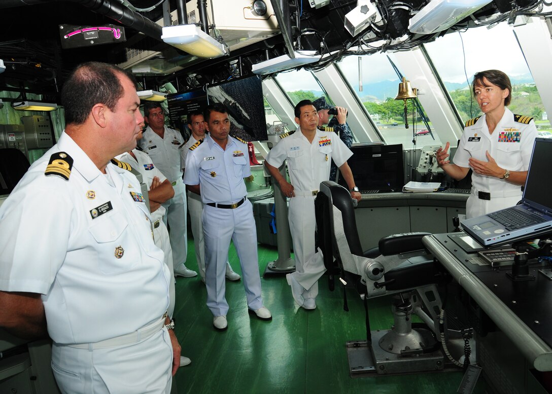 U.S. Navy Cmdr. Kris Doyle, commanding officer of the littoral combat ship USS Freedom, right, explains the ship's bridge to representatives of the 14 nations participating in Rim of the Pacific, June 27, 2010.