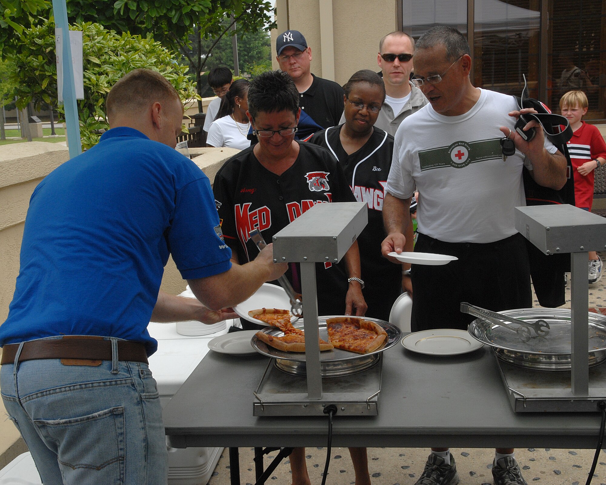KUNSAN AIR BASE, Republic of Korea -- Col. Steven Caberto, 8th Medical Group commander, and his wife Amy Caberto wait to be served pizza by Staff Sgt. Charles Nelson, 8th Security Forces Squadron, during Independence Day festivities here July 4. The Pizza 4 Patriots Operation World Pizza program provided 48 Chicago-style deep-dish pizzas to Kunsan for the Wolf Pack to enjoy a "slice of home" during the holiday. (U.S. Air Force photo/Senior Airman Roy Lynch)