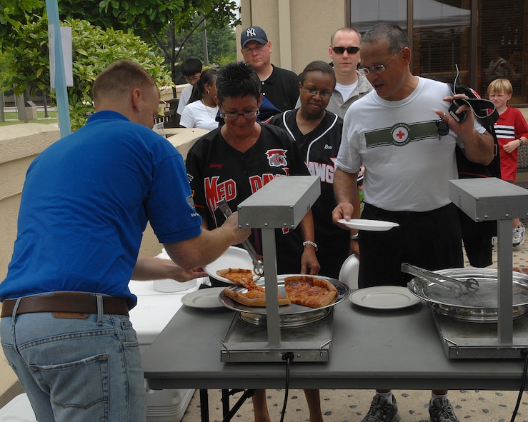 KUNSAN AIR BASE, Republic of Korea -- Col. Steven Caberto, 8th Medical Group commander, and his wife Amy Caberto wait to be served pizza by Staff Sgt. Charles Nelson, 8th Security Forces Squadron, during Independence Day festivities here July 4. The Pizza 4 Patriots Operation World Pizza program provided 48 Chicago-style deep-dish pizzas to Kunsan for the Wolf Pack to enjoy a "slice of home" during the holiday. (U.S. Air Force photo/Senior Airman Roy Lynch)