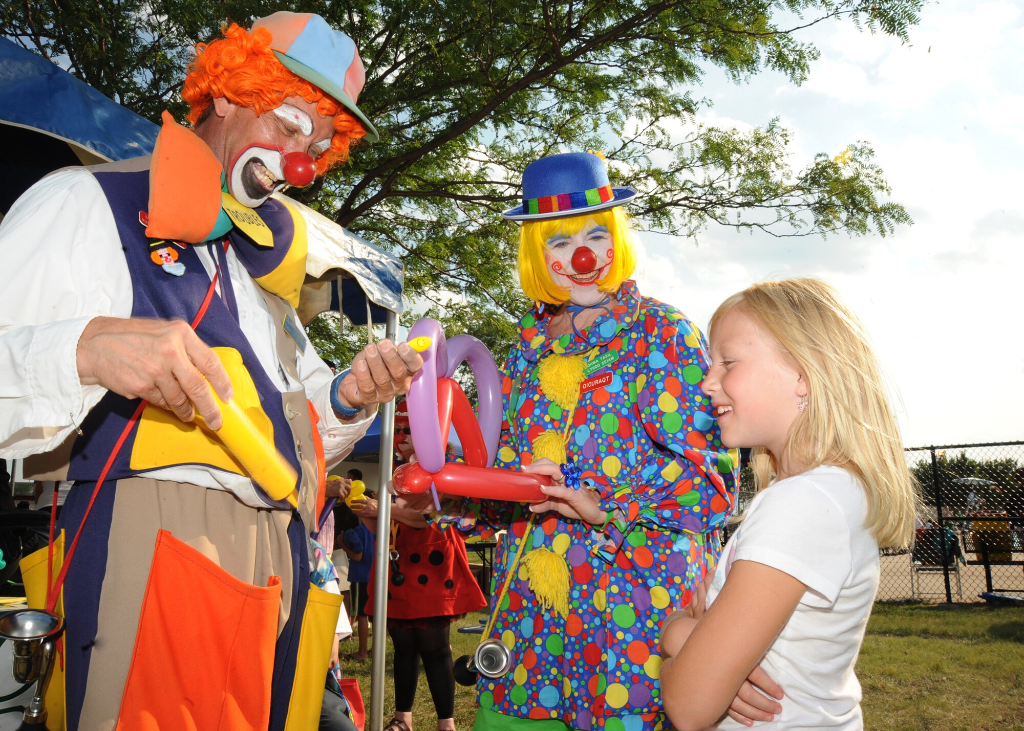 Clowns from the Ambassadors of Good Will Clown association make a balloon hat for Allison Mehringer, 8, daughter of Master Sgt. Jonathan Mehringer, 22nd Security Forces Squadron installation security superintendent, during a beach party July 1, 2010, McConnell Air Force Base, Kan.  The 22nd Force Support Squadron   is responsible for providing the best quality of life programs for more than 5,615 military personnel and their family members.  The party gave Team McConnell members time to participate in outdoor activities and safely prepare for the Fourth of July holiday.  (U.S. Air Force photo/ Senior Airman Maria Ruiz)
