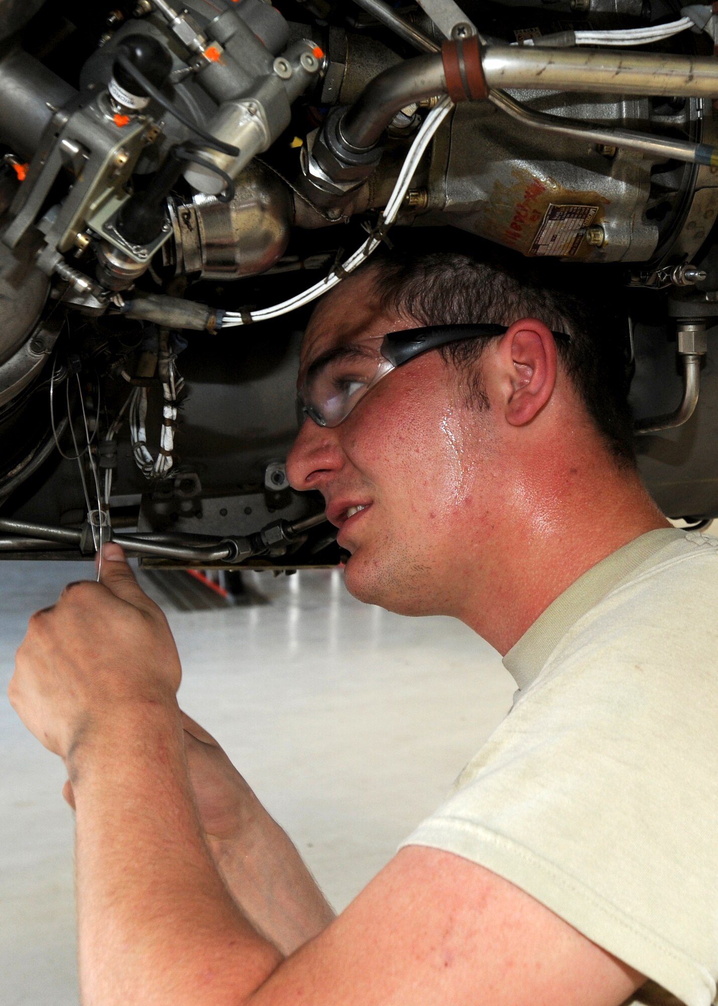Airman Troy Howard, 22nd Maintenance Squadron aerospace propulsion journeyman, sweats while applying safety wire to an engine of a KC-135 Stratotanker June 22, 2010, McConnell Air Force Base, Kan.  During the summer, heat injuries and conditions are something all McConnell Airmen should be aware of and take steps to prevent.  To protect themselves and each other, Airmen should remember to drink plenty of water, wear lightweight, light-colored and loose-fitting clothing and limit sun exposure during the mid-day hours.   (U.S. Air Force photo/Airman 1st Class Andrea Salazar) 