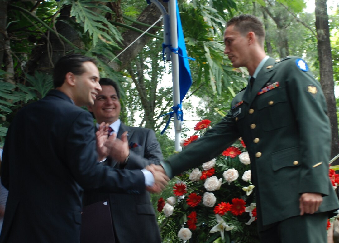 Spc. Eniol Abreusarmiento, a helicopter mechanic and crew chief in the 1-228th Aviation Regiment, Soto Cano Air Base, Honduras, shakes hands with Emigdio Martinez, the field office director for the Office of Citizenship and Immigration Services, after taking the naturalization oath during a ceremony in Tegucigalpa July 2. Specialist Abreusarmiento, who was born in Cuba, became a U.S. citizen at an Independence Day celebration hosted by U.S. Ambassador to Honduras Hugo Llorens and attended by Honduran President Porfirio Lobo. (U.S. Air Force photo by 1st Lt. Jen Richard)