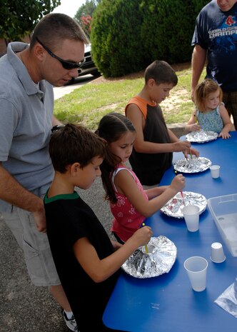Tech. Sgt. Michael Bradford with sons Dominic, front, and Peyton, back, and neighborhood friend Emma Farris make toy volcanoes during the summer reading program at the base library June 30, 2010 on Joint Base Charleston, S.C. Children learned about volcanoes during the live reading and then proceeded to make their very own miniature volcanoes outside the base library. All programs and activities are planned with elementary children in mind, but all ages are welcome to participate. Emma, age 7, is the daughter of Master Sergeant Jason Farris. Sergeant Bradford is an equipment operator with the 628th Civil Engineer Squadron and Sergeant Farris is the ramp chief for the 437th Aerial Port Squadron. (U.S. Air Force photo/Senior Airman Timothy Taylor)