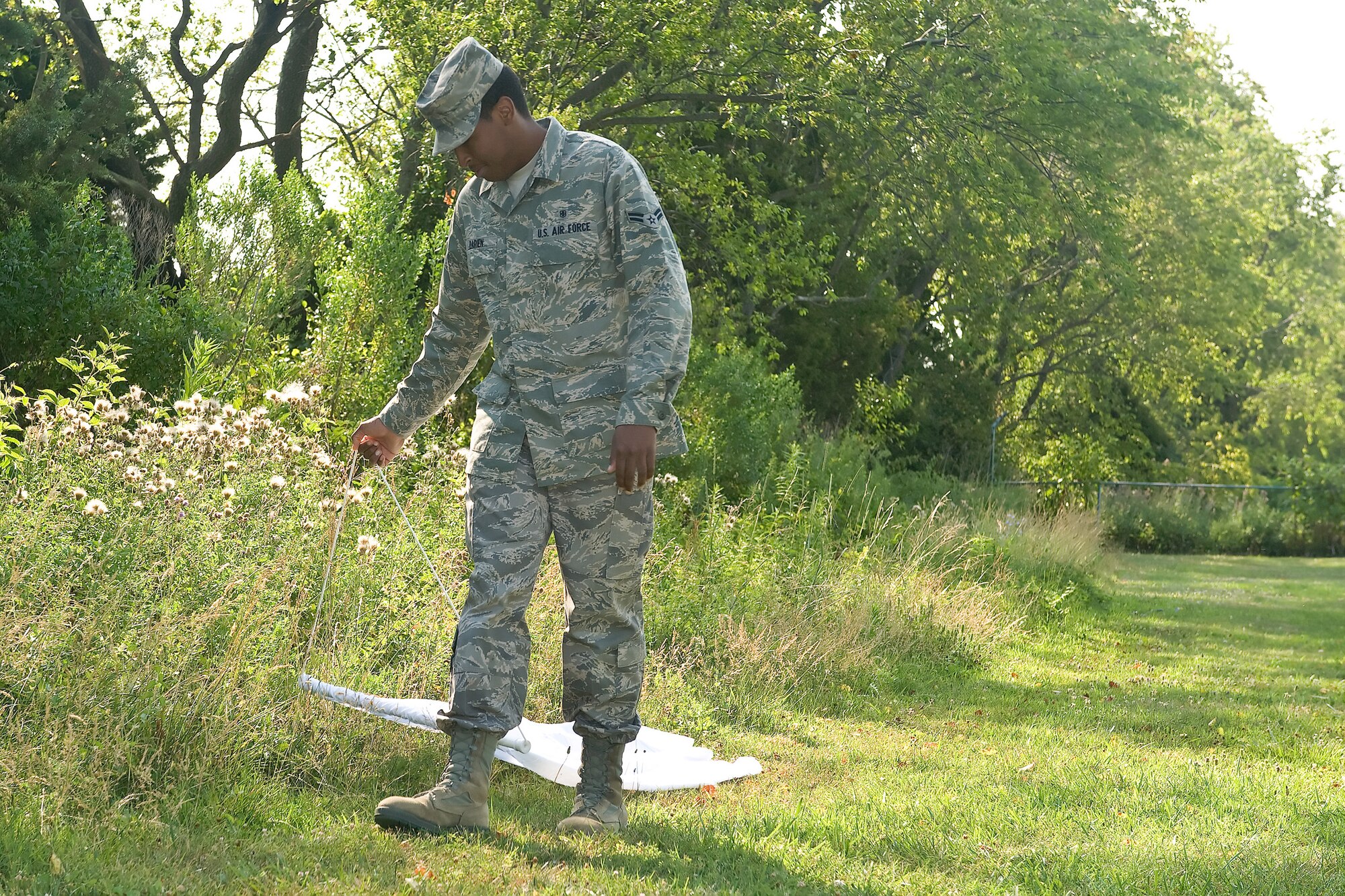 Airman 1st Class Delvin Darien, 436th Aerospace Medicine Squadron Public Health Flight Technician, runs a piece of cloth along a grassy area at the Eagle?s Rest Picnic Area on Dover Air Force Base, Del., June 30, 2010. Darien uses this method of tick-hunting to trap the critter to test for lyme disease. (U.S. Air Force photo by Roland Balik/Released)