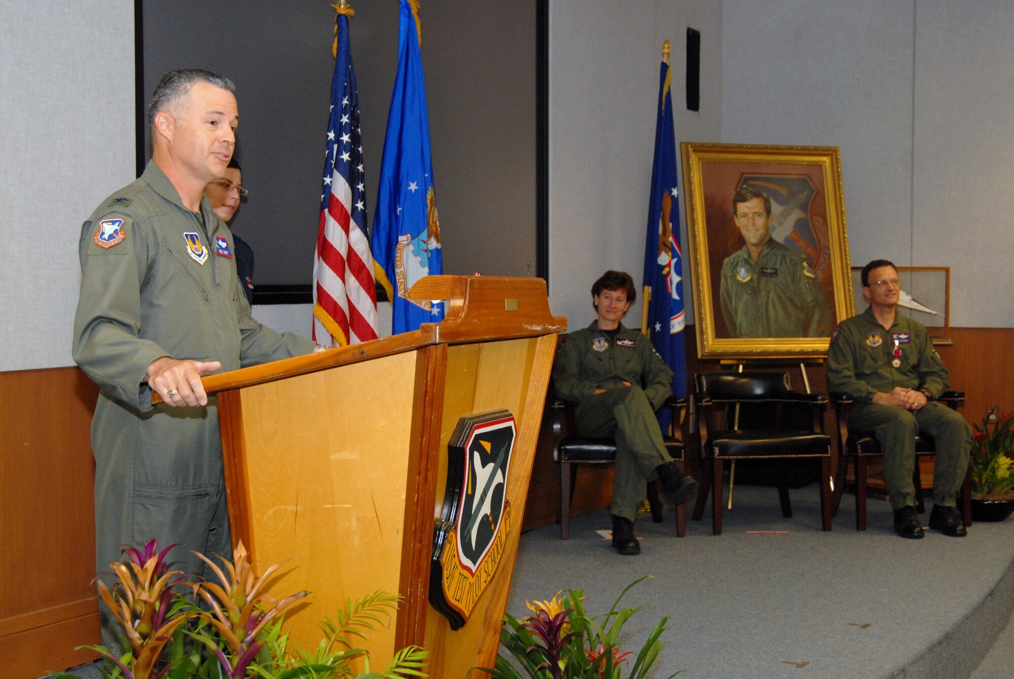 Col. Noel Zamot speaks to a standing-room only crowd in the U.S. Air Force Test Pilot School's Dick Scobee Auditorium as Col. Dawn M. Dunlop, 412th Test Wing commander, and Col. Terry M. Luallen look on from the stage.  Colonel Zamot assumed the role of 39th commandant of the TPS from Colonel Luallen July 7. (Air Force photo by Kenji Thuloweit) 