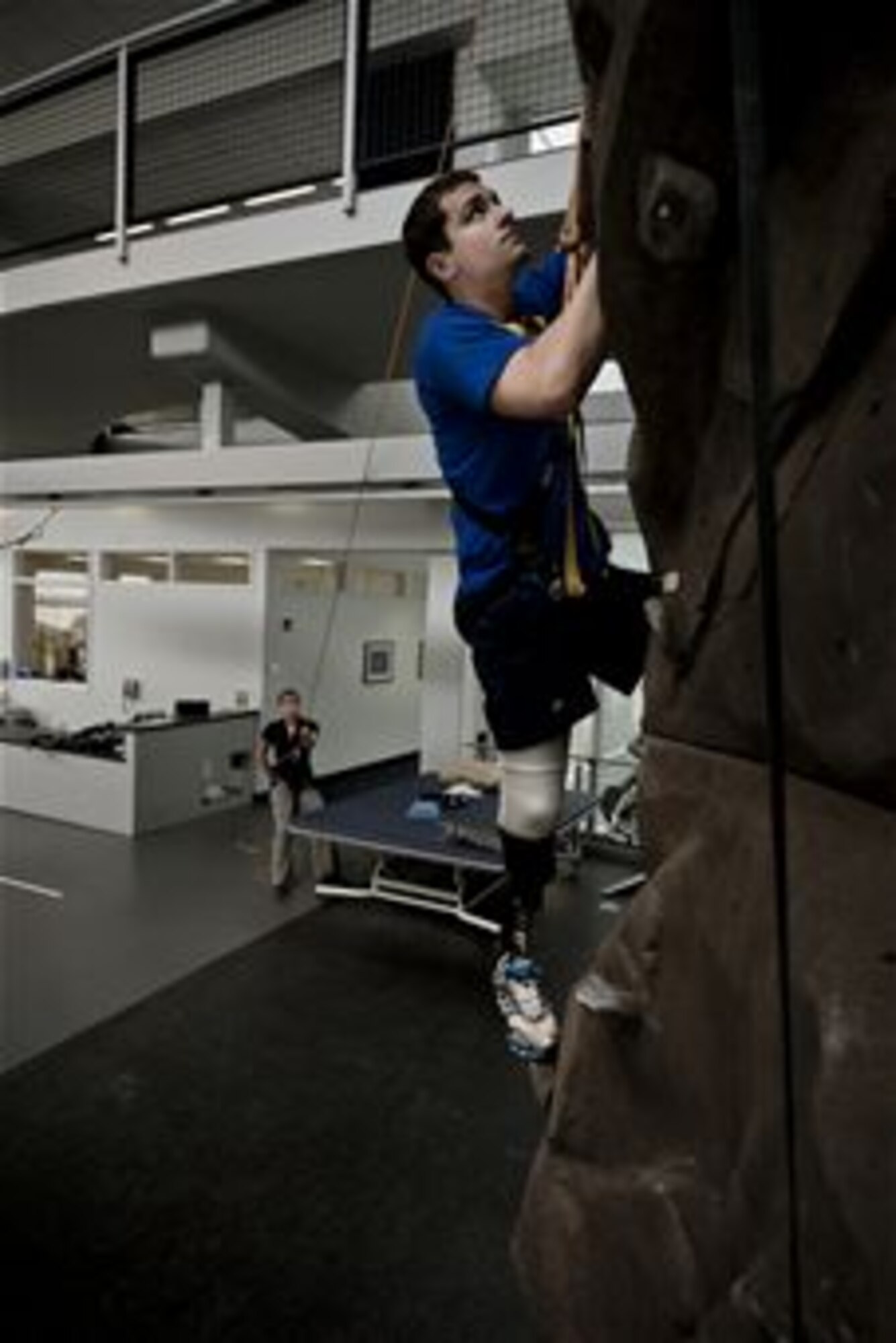 Conquering the rock climbing wall at the Center for the Intrepid is just one of the exercises physical therapist Alicia White (holding the safety rope) has McGuire perform. The rehabilitation therapy helps the lieutenant get used to the prosthetic he received after having his lower right leg amputated following a boating mishap last summer. (TSgt Samuel Bendet)
