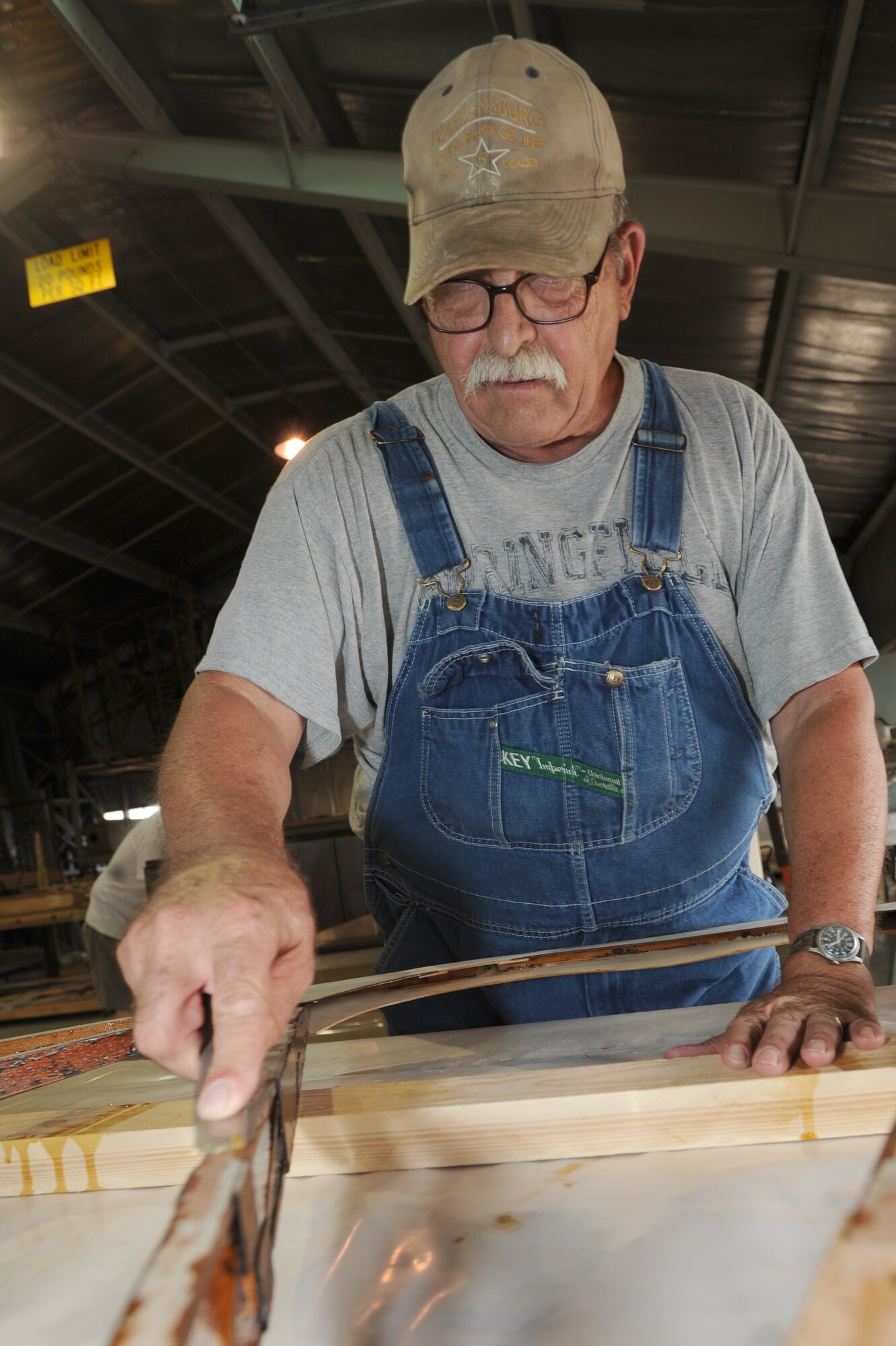 WHITEMAN AIR FORCE BASE, Mo. - Arthur Miller, Waco glider restoration project volunteer, scrapes of polyurethane from the supports of the rudder, prepping it for another coat, July 7. The surfaces of the wings, rear stabilizers and rudder must be smooth to receive the fabric that will be stretched later in the restoration process.(U.S. Air Force photo/ Senior Airman Carlin Leslie)(Released)
