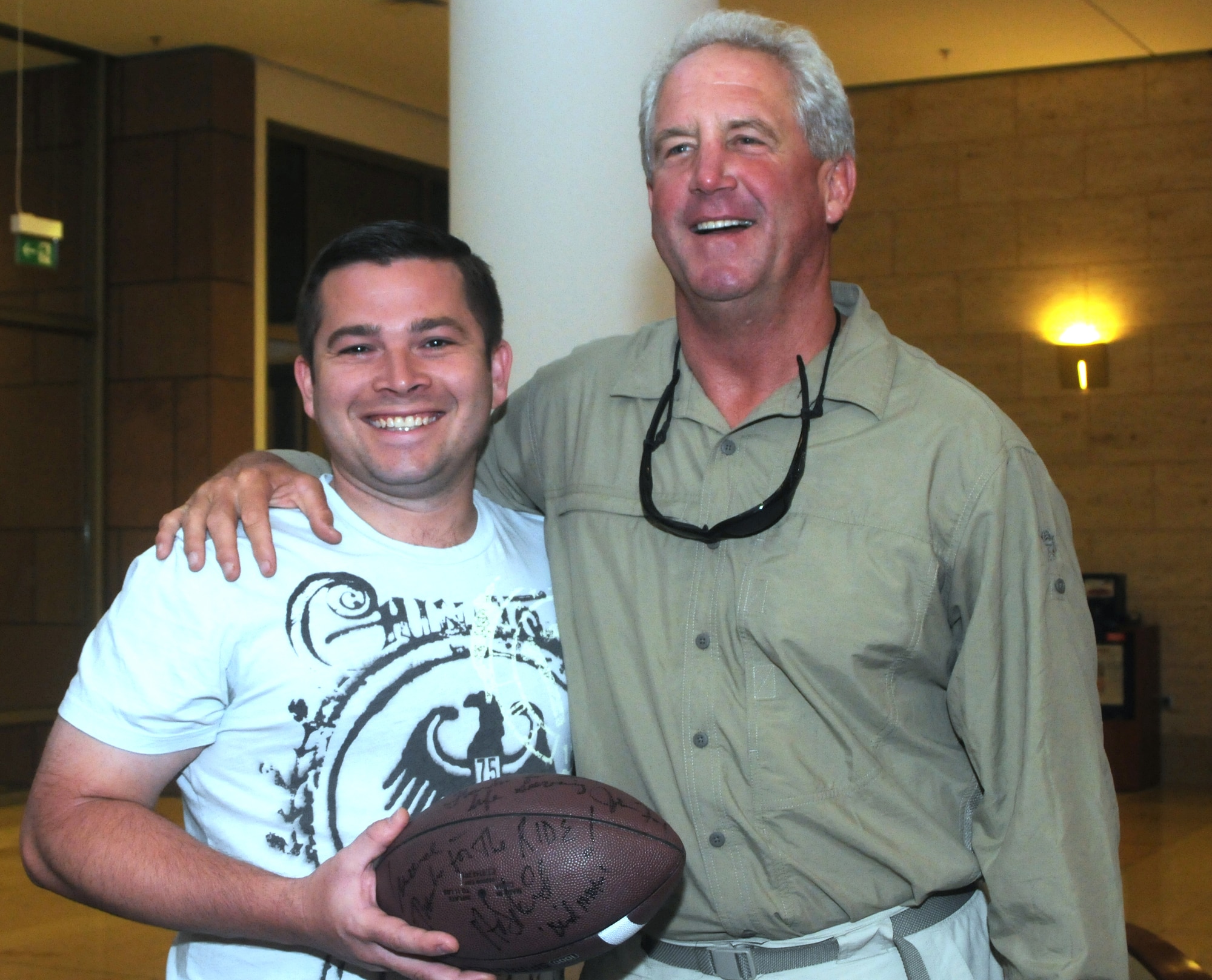 Coach John Fox, Carolina Panthers head coach, stops to take a photo after signing a football for Capt. Lawrence Dingler, a pilot with the 326th Airlift Squadron, Dover Air Force Base, Del., at the Eagles Rest Inn on Ramstein Air Base, Germany, July 1. The aircrew picked up the four National Football League coaches who were participating in the 2010 NFL-USO Coaches' tour. The crew was slated to transport the coaches to Bagram Air Base, Afghanistan. (U.S. Air Force photo/Senior Airman Andria J. Allmond)
