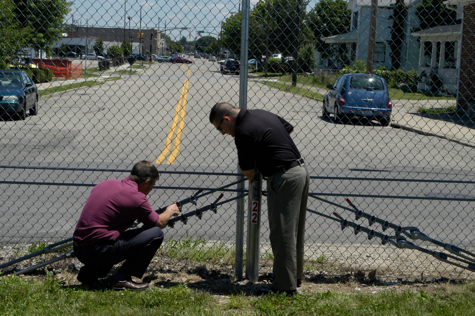 Antiterrorism Installation Officer's Mark Myers and Nick Phillips inspect recently installed fence cabling, which is used to secure safety. 