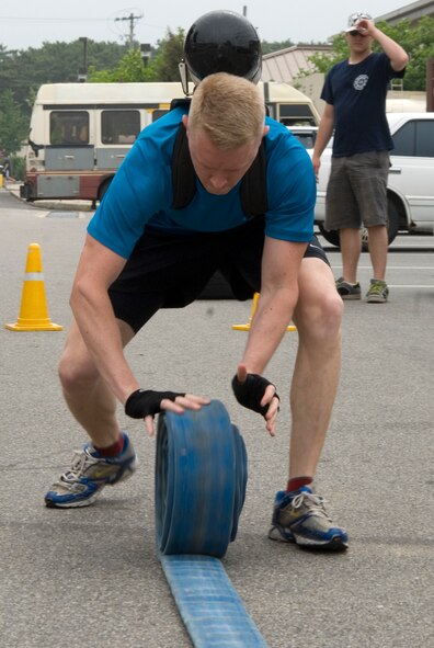 KUNSAN AIR BASE, Republic of Korea -- Capt. Jared Hand, 8th Operation Support Squadron weather flight commander, quickly rolls up a fire hose during the fire department relay race here July 4. Captain Hand's three-man team won the event finishing 10 different challenges with an overall time of 3 minutes and 14 seconds. In addition to the relay race, there was also a five kilometer run, cardboard boat race, a free barbecue and more, culminating in a fireworks show at the end of the night. (U.S. Air Force photo/Staff Sgt. Jonathan Pomeroy)