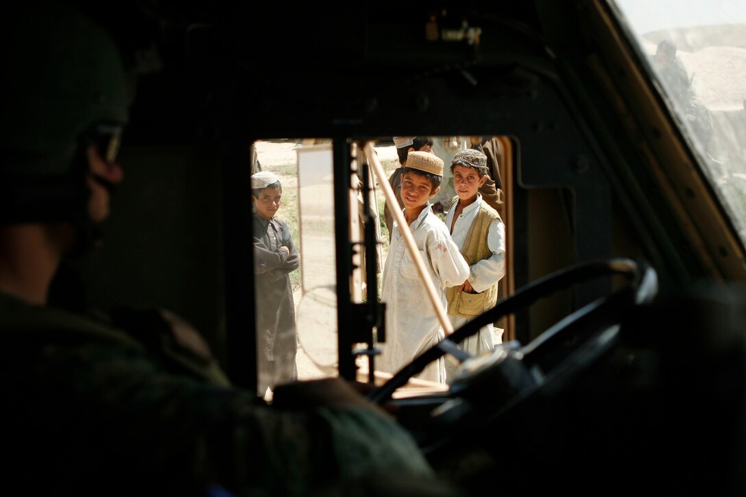 A Marine with a Marine Special Operations Team watches children out the window of his truck during a ground movement Moqur, Badghis Provence, Afghanistan July 7. ANA soldiers alongside U.S. Special Forces troops moved into Darrah-I-Bum to establish a Forward Operating Base there with the hopes of alleviating security issues in an area with heavy insurgent activity.