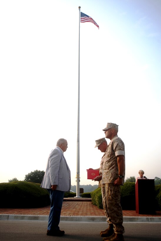 Richard M. Johnson (left) general foreman at the Ammunition Supply Point aboard Marine Corps Base Camp Lejeune, is presented with a certificate of commendation by Maj. Gen. Carl B. Jensen, commanding general of Marine Corps Installations East, for his combined 50 years of Department of Defense service after morning colors in front of Building 1, July 8. After 20 years in the Marine Corps, he retired as a gunnery sergeant and continued working in civil service to add on an additional 30 years of work.