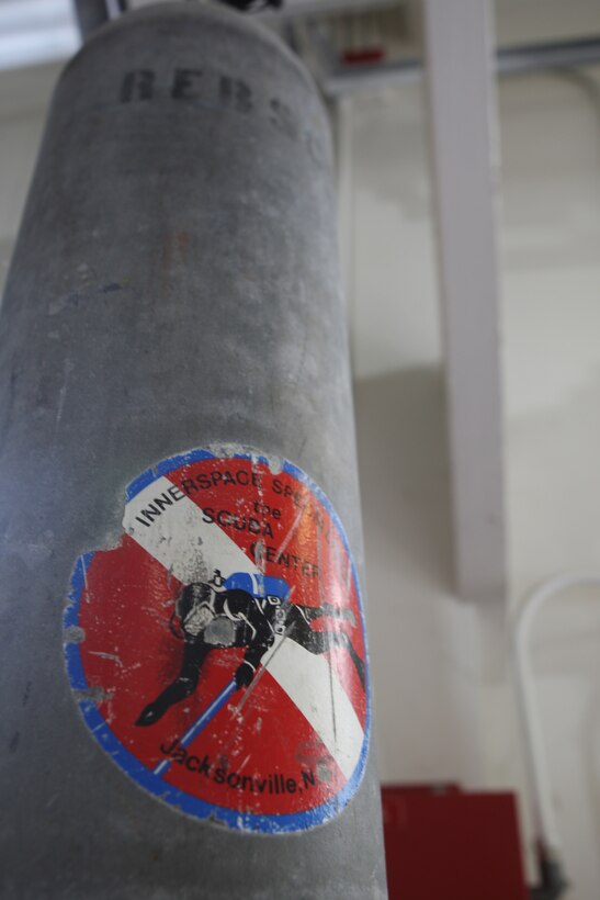 Hanging from the ceiling of the AA Diving shop aboard Marine Corps Base Camp Lejeune are several scuba tanks of various sizes, colors and volumes. Red and white diving flags are a common ornament of diving gear.