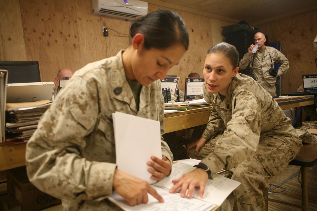 Sgt. Crystal Finegan, the career planner for 1st Marine Logistics Group, reviews re-enlistmant packages with Gunnery Sgt. Jeanette Santoro, the career planner for 3rd Marine Air Wing, at Camp Dwyer, Afghanistan, July 8. Marines from Regimental Combat Team 7 and other tenant units of Dwyer had the opportunity to re-enlist or obtain orders from their military occupational speciallty monitor. (U.S. Marine Corps Photo by Lance Cpl. Benjamin Crilly)