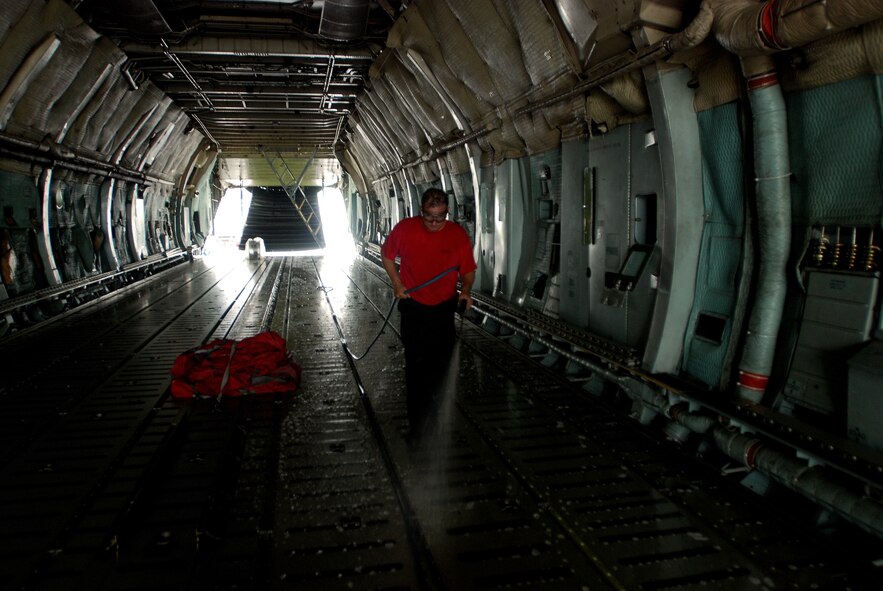 Michael Vekasy, project director for the contractor responsible for washing the C-5A Galaxy aircraft for the 433rd Airlift Wing, Lackland Air Force Base, Texas, spraying a soap and water mixture on the floor of the aircraft's cargo hold. (U.S. Air Force photo/Airman 1st Class Brian McGloin)