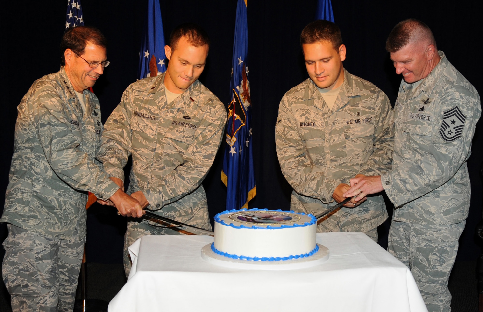 SMC commander, Lt. Gen. Tom Sheridan and Chief Master Sgt. Mark Repp are joined by SMC’s youngest officer, Lt. David Fondacaro and SMC’s youngest enlisted person, Airman Tyler Ritchey, in cutting the cake marking the center’s 56th birthday, July 1.  (Photo by Lou Hernandez)