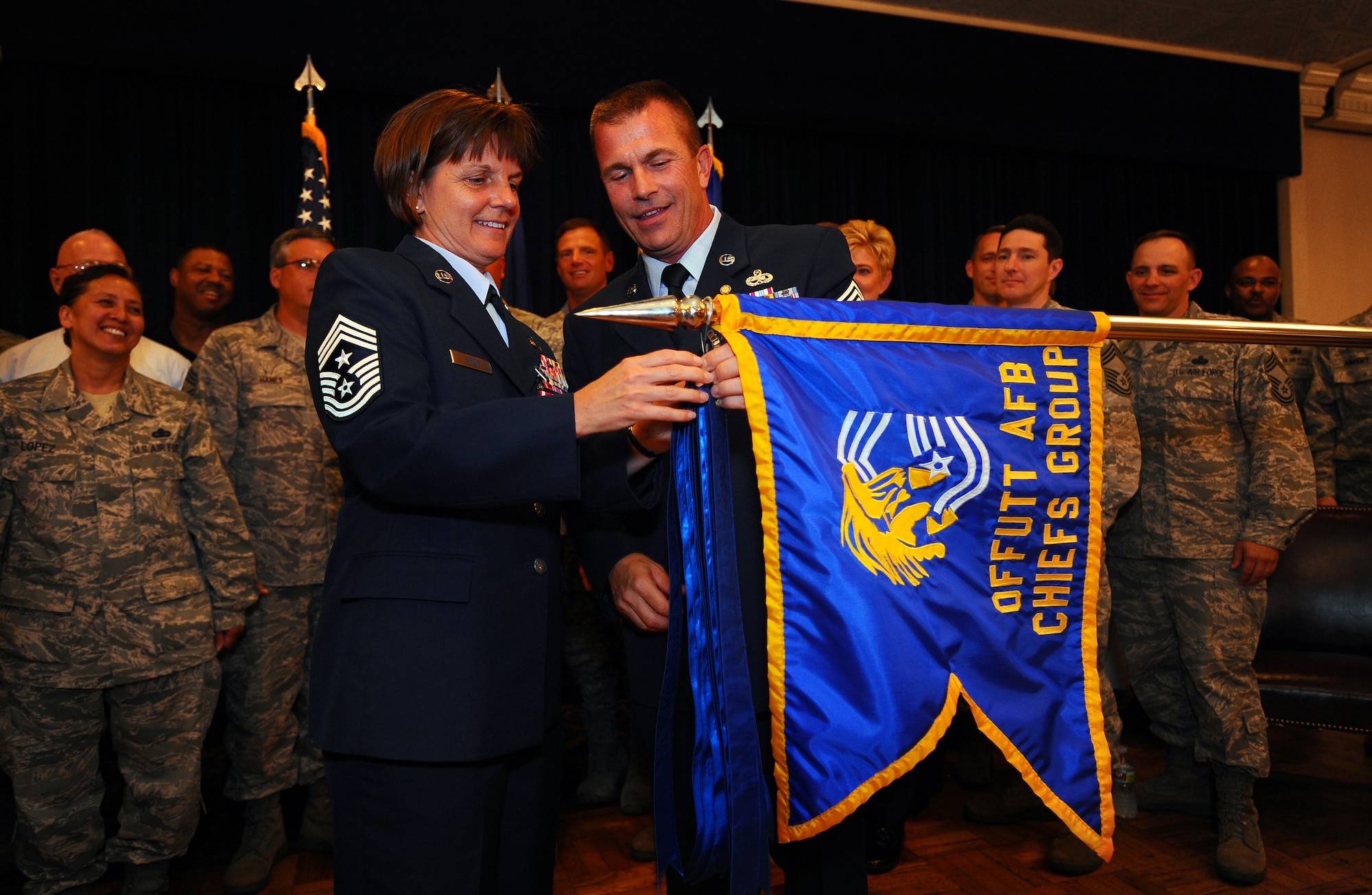OFFUTT AIR FORCE BASE, Neb. - Command Chief Master Sgt. Lisa Sirois and her husband, Chief Master Sgt. Roger Sirois, add their streamers to the Chief's Group guidon during their dual retirement ceremony at the Patriot Club, July 6.  With over 60 years of combined service, Chiefs Lisa and Roger Sirois' retirement ceremony symbolized both a commitment to the service of this country as well as one another. U.S. Air Force photo by Josh Plueger
