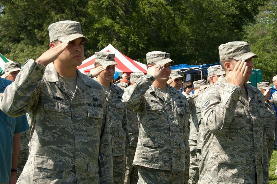 HANSCOM AIR FORCE BASE, Mass. – Senior Airman Robert T. Harms (left) and other Airmen salute during the Heroes Homecoming event on June 25. Thirty-eight Airmen who have recently returned from deployments and their families were honored during the ceremony at Memorial Park. (U.S. Air Force photo by Rick Berry)