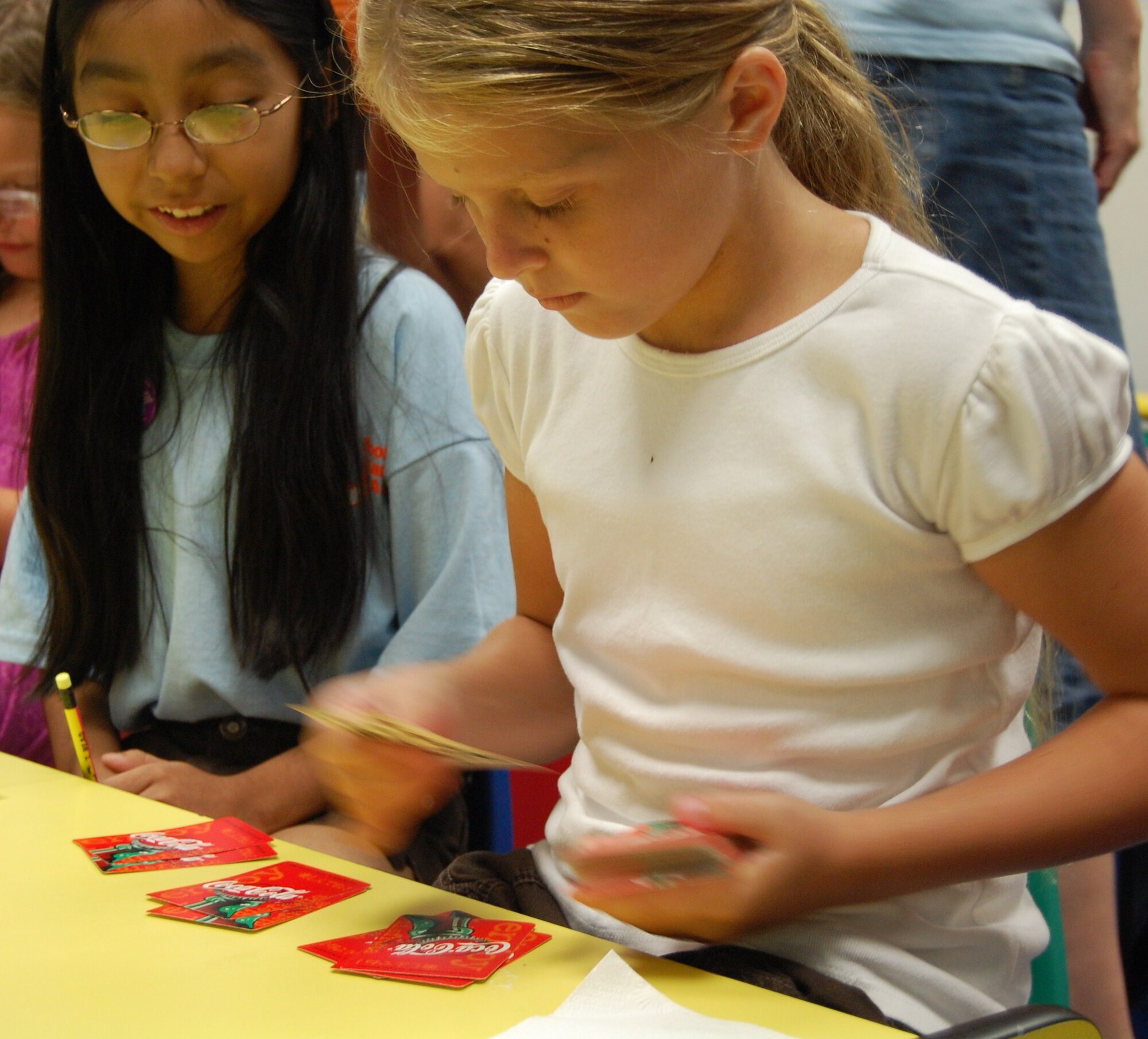 LAUGHLIN AIR FORCE BASE, Texas ¬¬– Sutton Dalrymple (right) deals cards to play “Go Fish” while Isamar Rodriquez (left) checks her card dealing accuracy at the Laughlin library’s summer reading program July 6.  The kid’s summer reading program meets every Tuesday through Aug. 3 and revolves around the theme “Voyage to Book Island”. During the program, the kids participate in several different activities and have a snack in addition to a book being read aloud to them. (U.S. Air Force Photo by Staff Sgt. Desiree Economides)